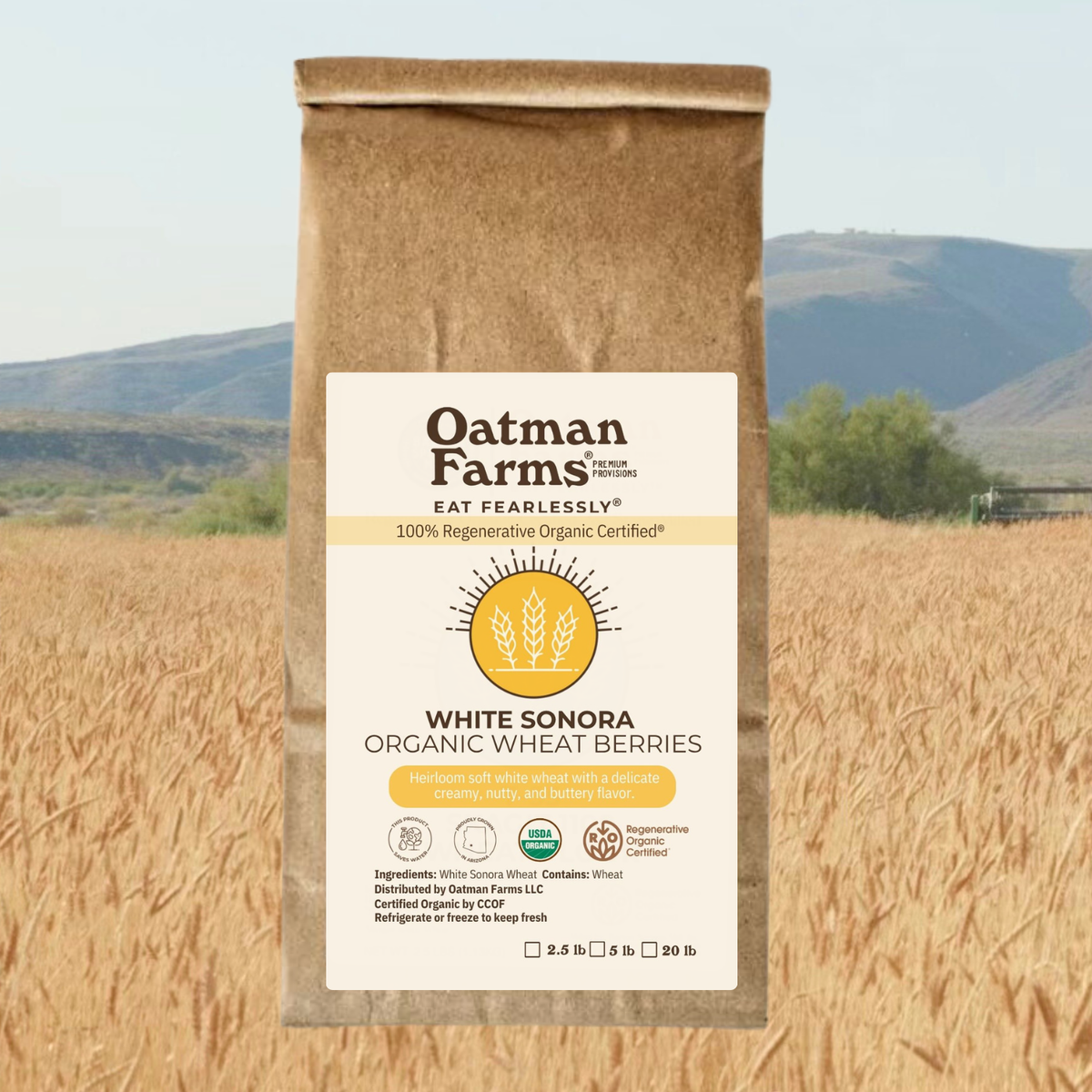 composite image of a bag of Oatman Farms wheat berries ROC® White Sonora Wheat Berries imposed over a wheat field with mountains in the background.